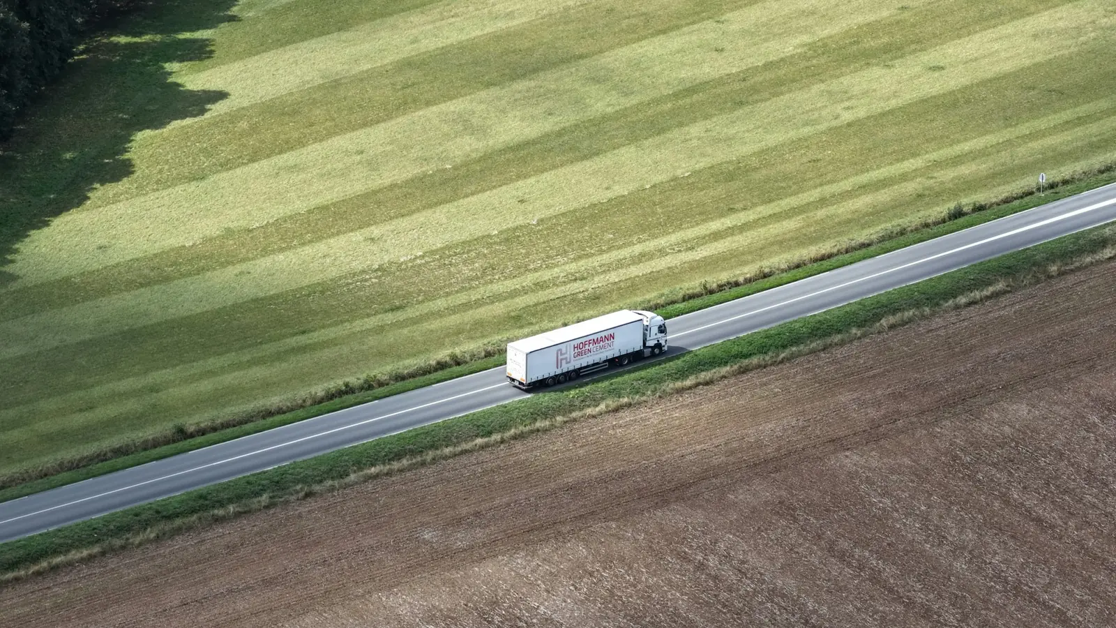A truck driving on a highway through open fields