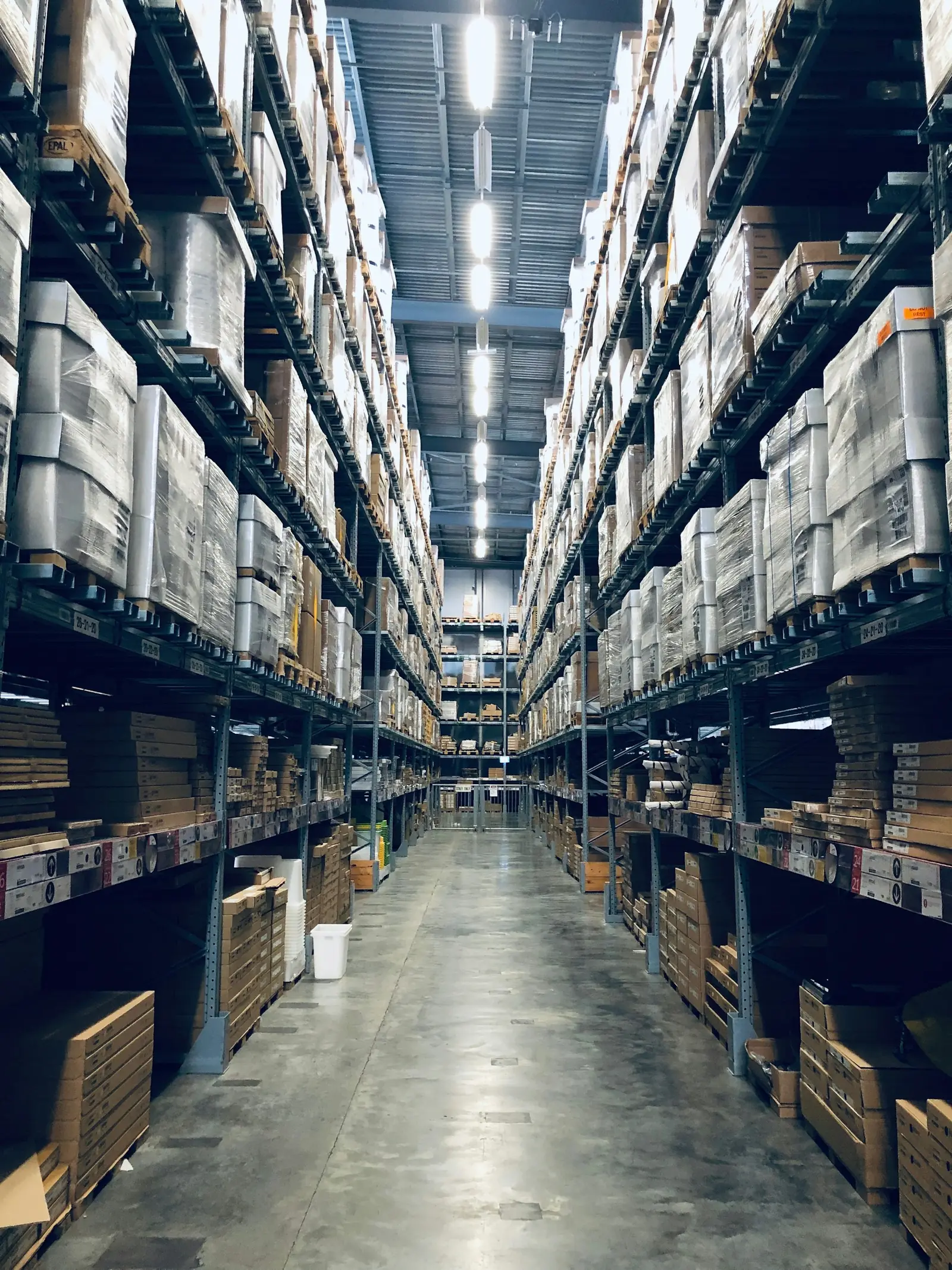 A long warehouse aisle lined with stocked shelves